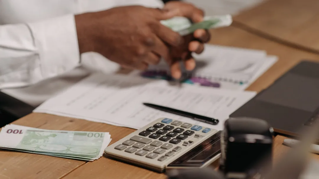 Empreendedor contando dinheiro com calculadora e relatórios
