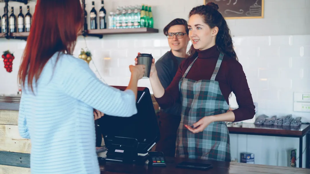 Barista atendendo um cliente no balcão da cafeteria