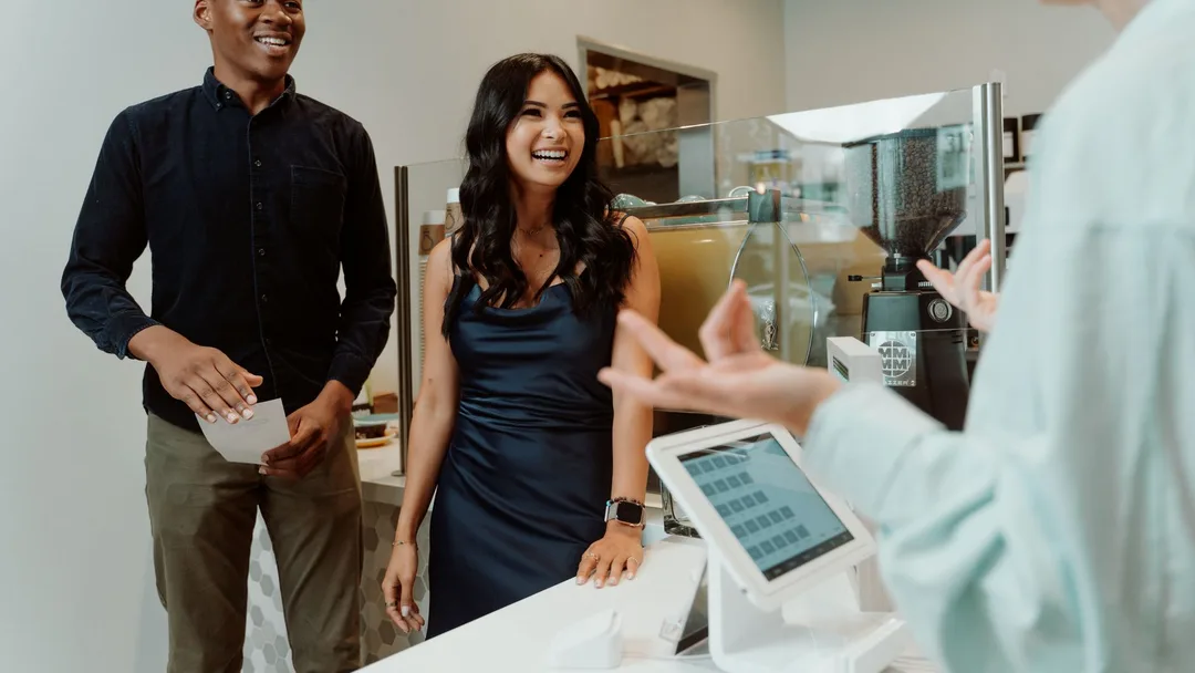 Casal de clientes sorrindo no balcão de uma cafeteria