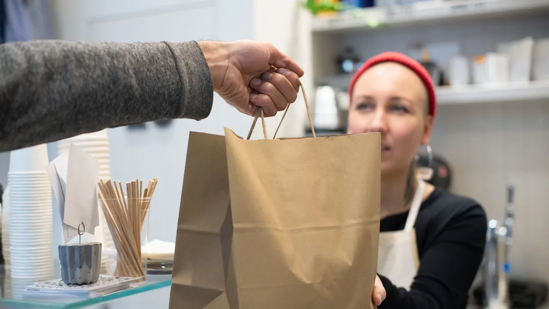 Atendente entregando uma sacola para o cliente num café